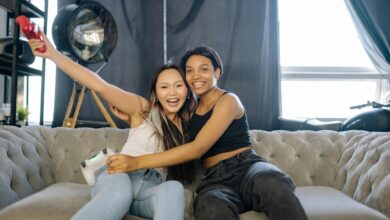 Two friends enjoying video games indoors, smiling and having fun on a comfortable couch.