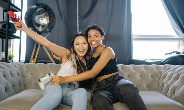 Two friends enjoying video games indoors, smiling and having fun on a comfortable couch.