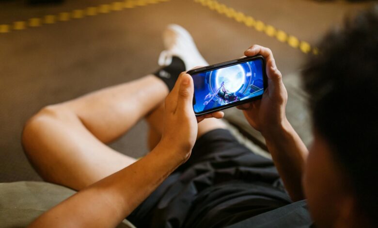 Man playing a video game on a smartphone while sitting comfortably indoors.