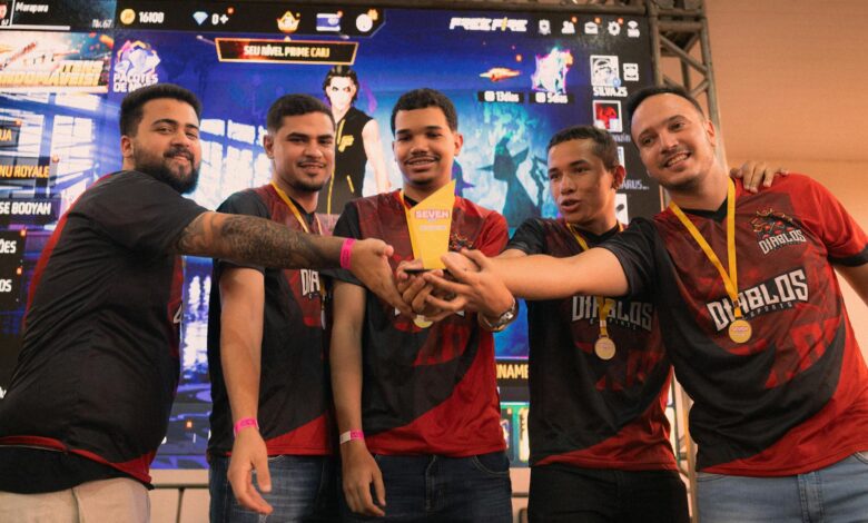 A group of gamers celebrating their victory at an e-sports event holding a trophy.