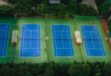 Tennis courts from above showcasing players in action, surrounded by greenery.