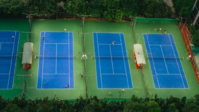 Tennis courts from above showcasing players in action, surrounded by greenery.