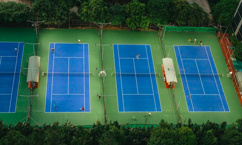 Tennis courts from above showcasing players in action, surrounded by greenery.