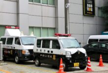 Police vans in Tokyo, Japan, parked outside a building with traffic cones.