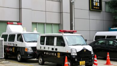 Police vans in Tokyo, Japan, parked outside a building with traffic cones.