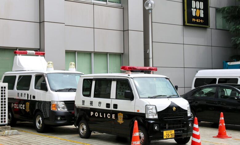 Police vans in Tokyo, Japan, parked outside a building with traffic cones.