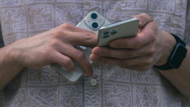 Detail of hands holding two smartphones, showcasing modern technology usage.
