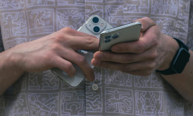 Detail of hands holding two smartphones, showcasing modern technology usage.