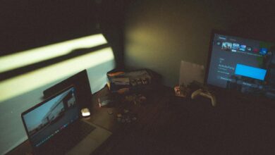 Dark room with a laptop and gaming console creating a moody tech atmosphere.