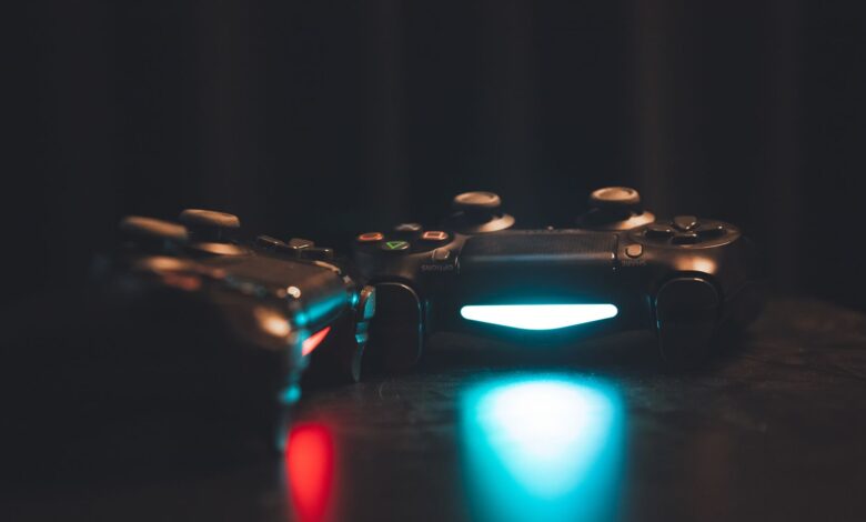 Close-up of glowing gaming controllers on a dark surface, creating a moody ambiance.