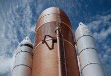 Dramatic view of rocket boosters against a bright blue sky, showcasing aerospace technology.