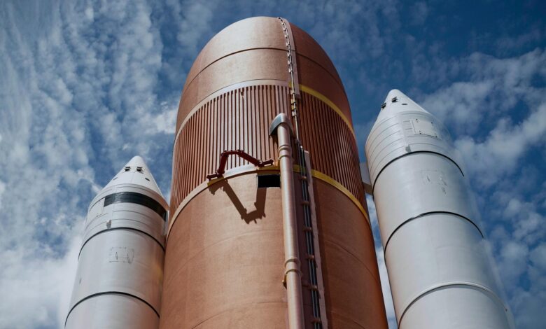 Dramatic view of rocket boosters against a bright blue sky, showcasing aerospace technology.
