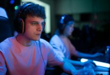 Man with headset engaged in intense gaming session under neon lights.