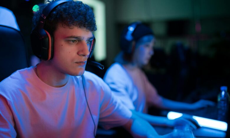 Man with headset engaged in intense gaming session under neon lights.