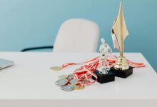 A collection of trophies and medals displayed on a white desk, symbolizing success and victory.