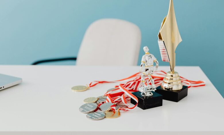 A collection of trophies and medals displayed on a white desk, symbolizing success and victory.