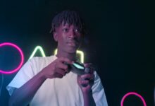 Serious young man playing video games in a neon-lit environment, focused and immersed.