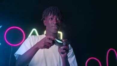 Serious young man playing video games in a neon-lit environment, focused and immersed.