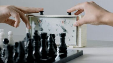 Close-up of hands pressing chess clock during an intense board game session.