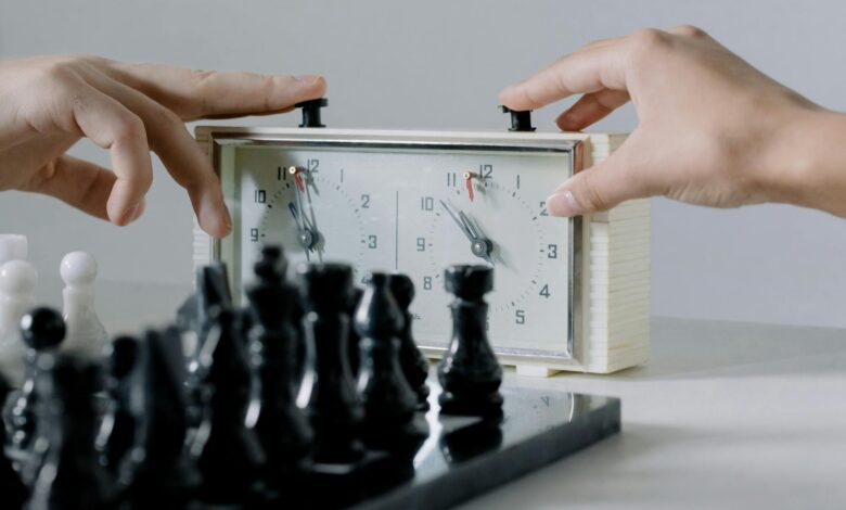 Close-up of hands pressing chess clock during an intense board game session.