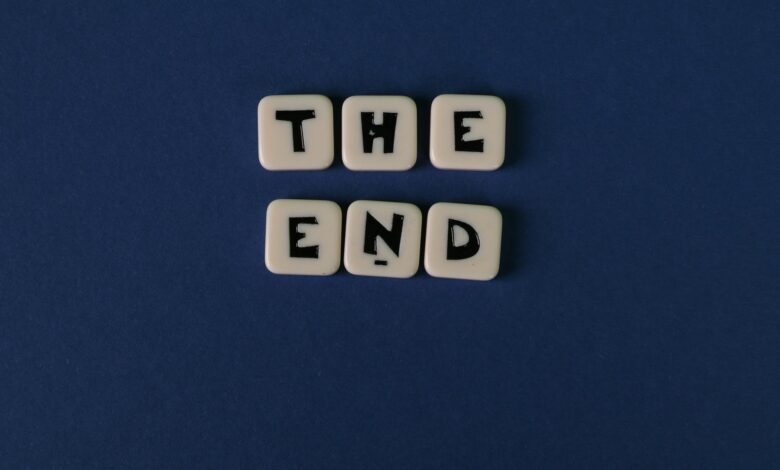 Scrabble tiles spelling 'The End' on a minimalist blue background. Perfect for conceptual designs.
