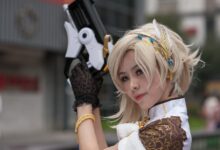 Cosplayer with intricate costume and prop gun, posing outdoors during the day.