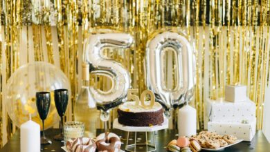 Stylish 50th birthday party setup with cake, gifts, and balloons in gold theme.