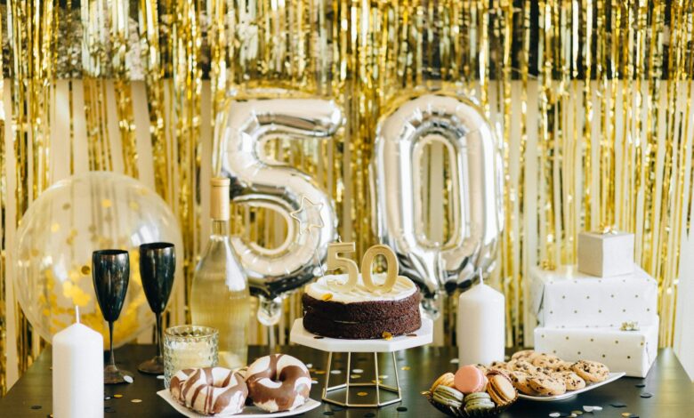 Stylish 50th birthday party setup with cake, gifts, and balloons in gold theme.