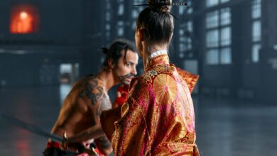 A dramatic scene of martial artists in traditional Japanese attire poised in confrontation within an industrial setting.