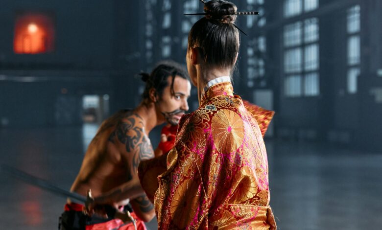 A dramatic scene of martial artists in traditional Japanese attire poised in confrontation within an industrial setting.