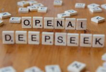 Close-up of wooden Scrabble tiles spelling OpenAI and DeepSeek on wooden table.