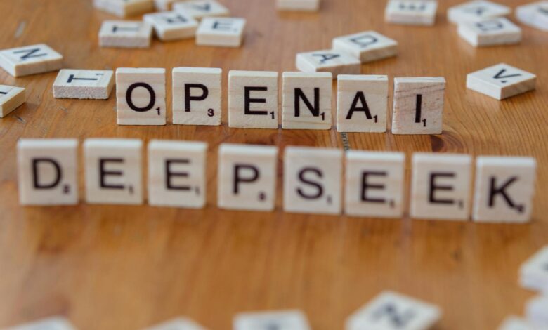 Close-up of wooden Scrabble tiles spelling OpenAI and DeepSeek on wooden table.