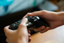Crop unrecognizable man with modern gamepad playing video game while having free time at home