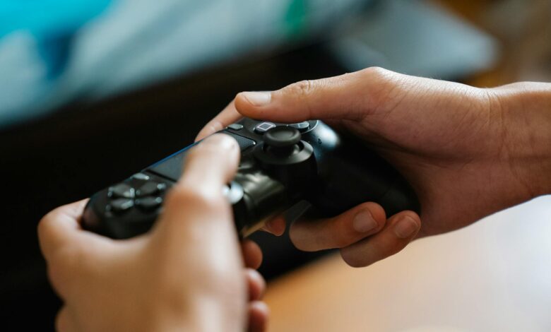 Crop unrecognizable man with modern gamepad playing video game while having free time at home