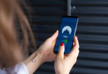 Close-up of a woman's hands using a VPN app on a smartphone, emphasizing digital security.
