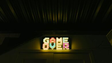 Glowing neon sign with pixelated Game Over text in a dark arcade setting.