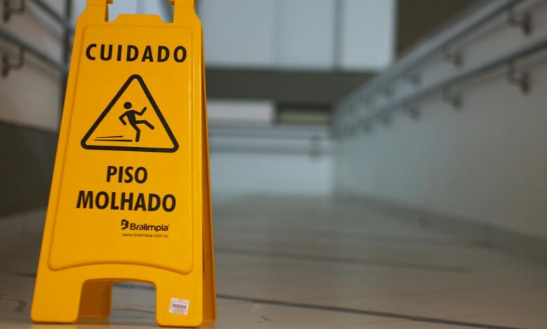 Yellow caution wet floor sign with Portuguese text in an indoor hallway.