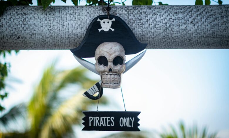 Decorative pirate skull sign with 'Pirates Only' text hanging outdoors on a sunny day.