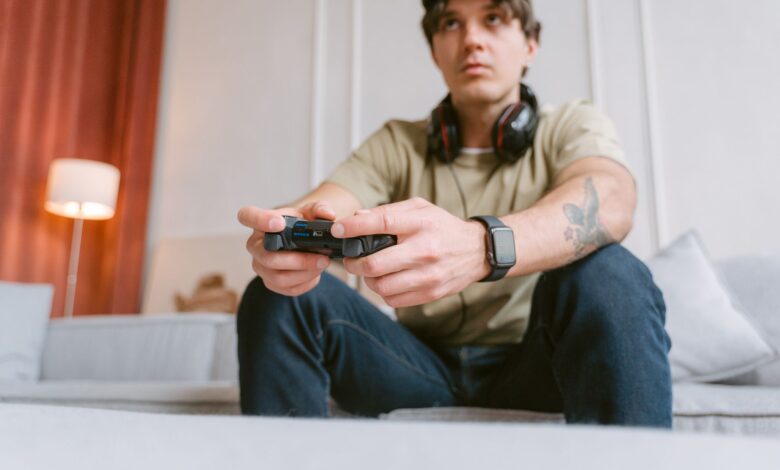 Young man focused on video gaming at home wearing headphones and a smartwatch.