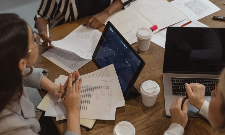 Business team collaborating with laptops and documents in a meeting, showcasing teamwork and cooperation.