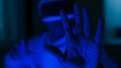 A person using VR glasses with outstretched hands in a futuristic blue-lit environment.