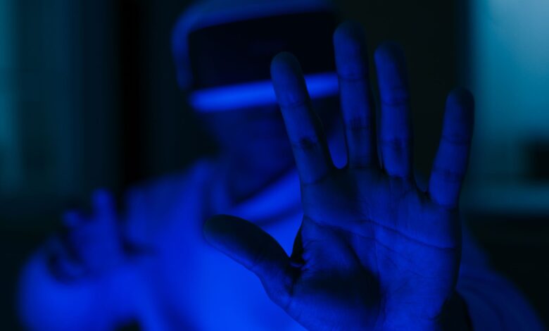 A person using VR glasses with outstretched hands in a futuristic blue-lit environment.