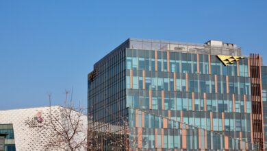 Two modern office buildings with glass facades under a clear blue sky.