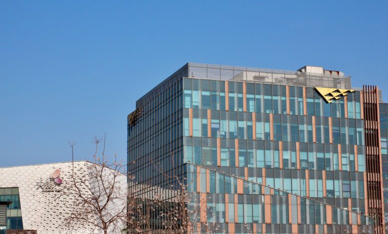 Two modern office buildings with glass facades under a clear blue sky.