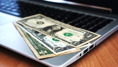 Close-up of US dollar bills placed on a laptop symbolizing digital finance and economy.