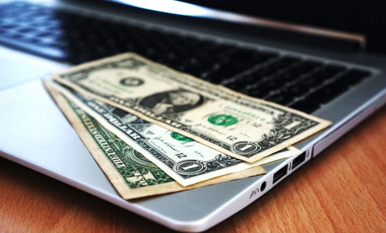Close-up of US dollar bills placed on a laptop symbolizing digital finance and economy.