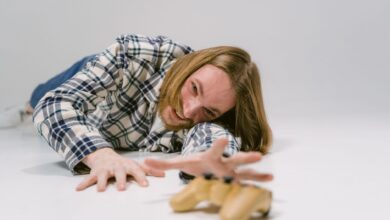 Man in plaid shirt reaching out to grab a gaming controller on a studio floor.