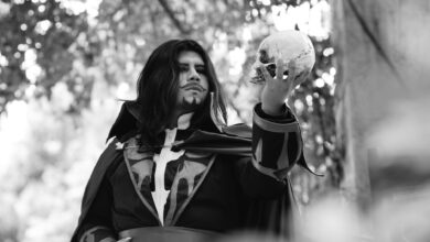 Black and white portrait of a man in costume holding a skull in an outdoor setting.