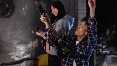 Two friends have fun playing a guitar simulation game indoors.