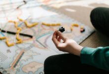 A person holding a game piece during a board game session indoors, showing strategy and leisure activity.